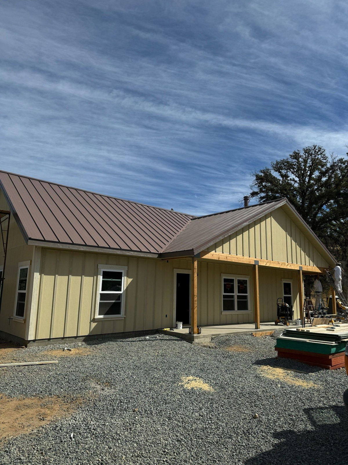 Finished single-story custom home in sage green board and batten with a bronze standing-seam metal roof