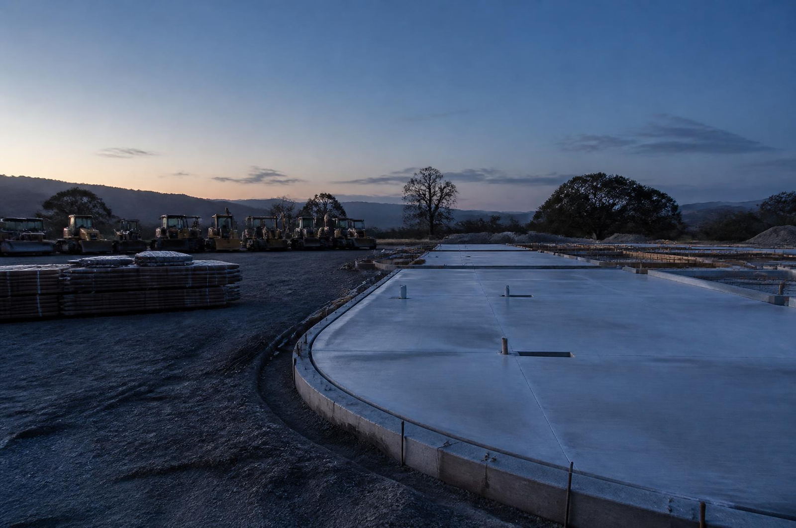 Immaculately organized Lane Built Inc. job site at dusk with equipment staged in a row